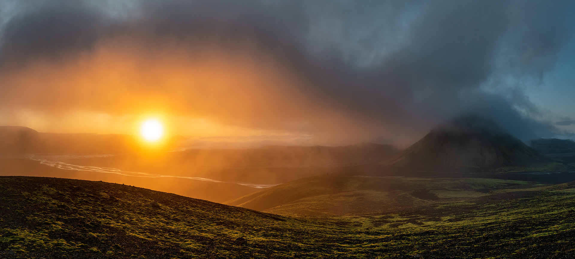 Witness the serene beauty of an Icelandic morning in this panoramic photo, where the rising sun pierces through morning mist, illuminating the highlands with a radiant glow. The early light reveals the contours and textures of the landscape, with a solitary mountain standing guard over the tranquil scene. This moment captures the essence of Iceland&rsquo;s rugged yet beautiful terrain, offering a glimpse into the country&rsquo;s natural splendor at the break of day.