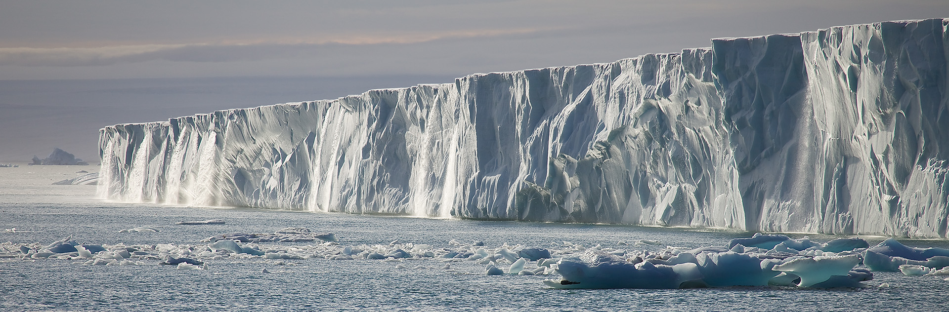 This image features the vast Austfonna ice cap on Nordaustlandet in the Svalbard archipelago, with its impressive ice cliffs plunging into the Arctic Ocean. The scene highlights the stark and pristine environment of the polar region, capturing the ice cap&rsquo;s grandeur and the tranquility of this remote locale. Ideal for bringing a sense of the planet&rsquo;s untouched wilderness into any space.