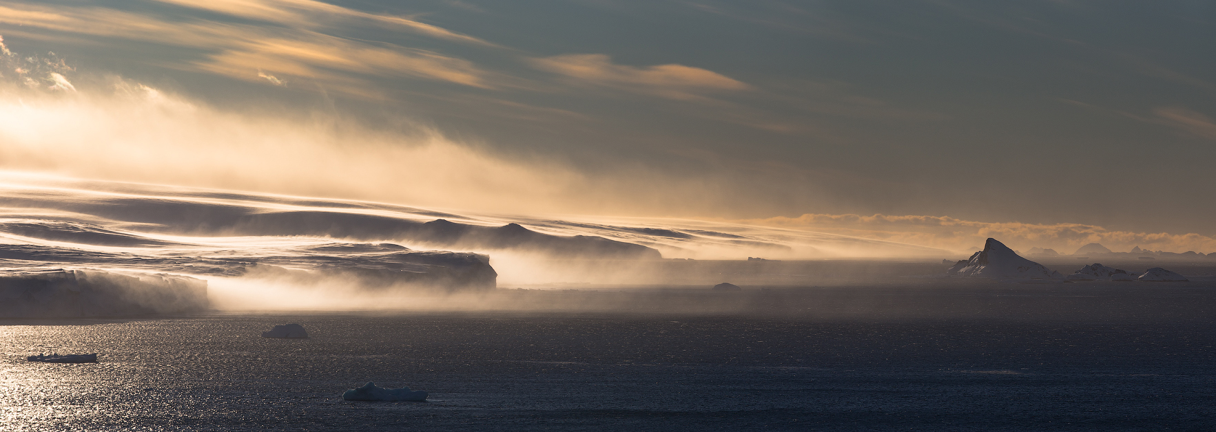 he raw power of nature is on full display in this evocative image, where strong winds whip up a snowstorm over the Arctic tundra. The sun&rsquo;s rays struggle through the swirling snow, creating a dynamic interplay of light and shadow. This photograph captures the untamed spirit of the Arctic wilderness, highlighting the beauty of a land shaped by the elements.